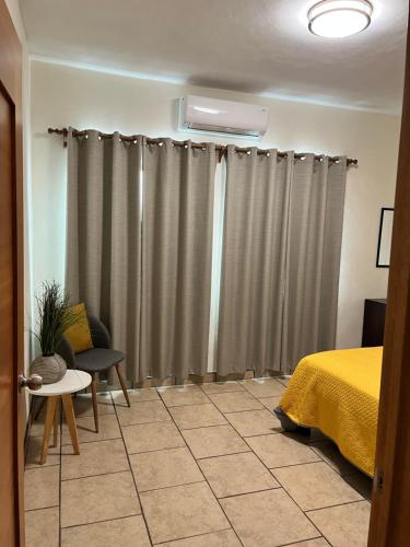 a bedroom with gray curtains and a yellow bed at Departamentos Hergoz in Ciudad Fernández