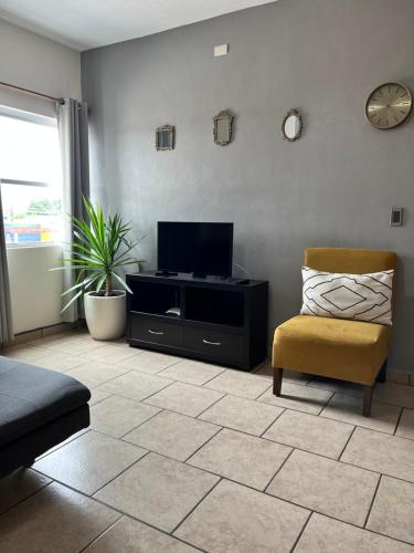 a living room with a tv and a chair at Departamentos Hergoz in Ciudad Fernández