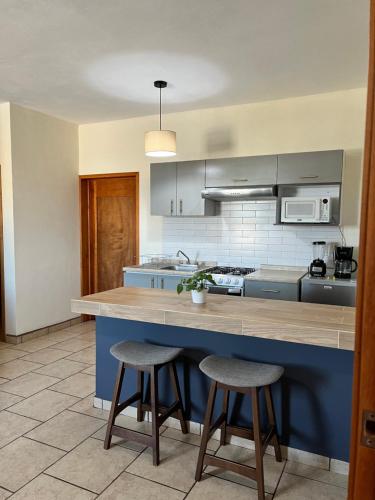 a kitchen with a blue island with two bar stools at Departamentos Hergoz in Ciudad Fernández