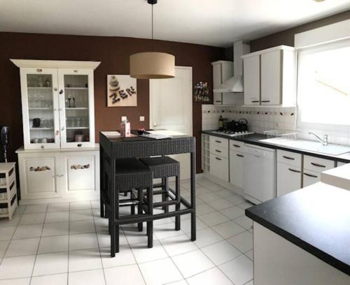 une cuisine avec des armoires blanches et une table et des chaises dans l'établissement Maison de village et paradis pour les enfants, à Châtillon-sur-Cher