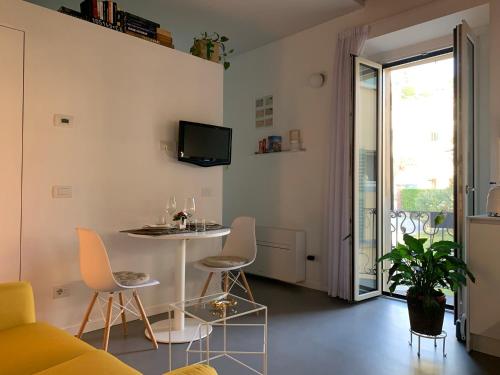 uma sala de estar com uma mesa e cadeiras e uma televisão em Villa Paola - Holiday Apartment - Menaggio, Lago di Como em Menaggio