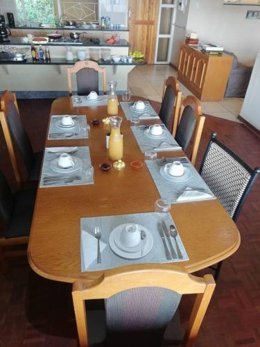 a wooden table with plates and utensils on it at Redberry Guest House in Mbabane