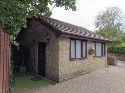 a small brick building with a door and a window at Lister Park Bradford Stylish 1bed Coach House - Quiet & Tranquil Cottage & Parking in Bradford