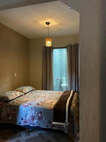- une chambre avec un grand lit et une fenêtre dans l'établissement Pousada Recanto Querubim, à Siqueira Campos