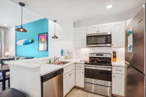 a kitchen with white cabinets and a stainless steel refrigerator at Madeira Bay Resort I 1505 in St Pete Beach