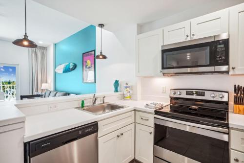 a kitchen with white cabinets and a sink and a microwave at Madeira Bay Resort I 1505 in St Pete Beach