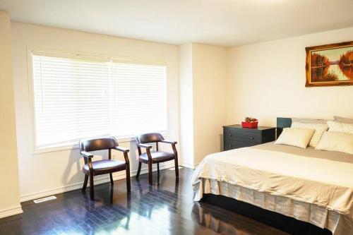 ein Schlafzimmer mit 2 Stühlen, einem Bett und einem Fenster in der Unterkunft Best staying place in town in Mississauga