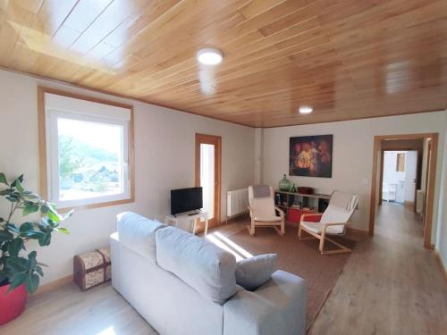 a living room with a white couch and a tv at Vila María in Castrelo de Miño