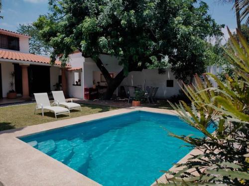 een zwembad voor een huis met een boom bij Hermosa casa en Cuernavaca cerca de los mejores restaurantes y plazas in Cuernavaca