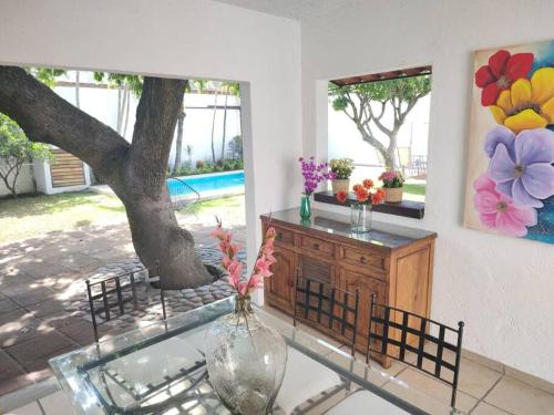 a glass table with a vase on a table with a tree at Hermosa casa en Cuernavaca cerca de los mejores restaurantes y plazas in Cuernavaca