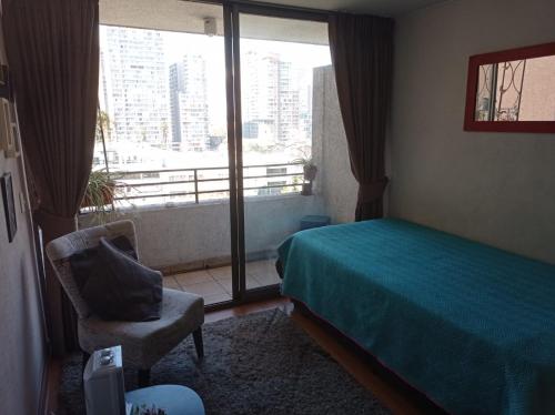 a bedroom with a bed and a chair and a window at Céntrico Departamento en Santiago in Santiago