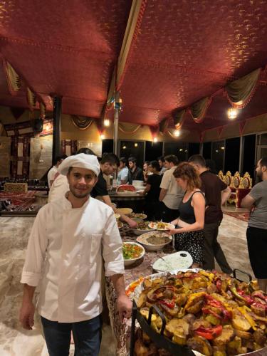 a chef standing in front of a table of food at Wadi Rum Fire Camp in Wadi Rum