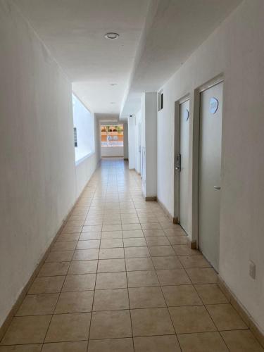 an empty hallway with white walls and a tile floor at Aló Select Mazatlan in Mazatlán