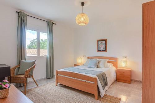 1 dormitorio con 1 cama, 1 silla y 1 ventana en Casa Herminia, en Coristanco