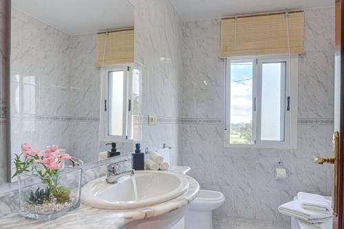 a white bathroom with a sink and a toilet at Casa Herminia in Coristanco