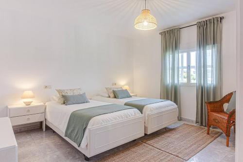 une chambre blanche avec deux lits et une fenêtre dans l'établissement Casa Herminia, à Coristanco