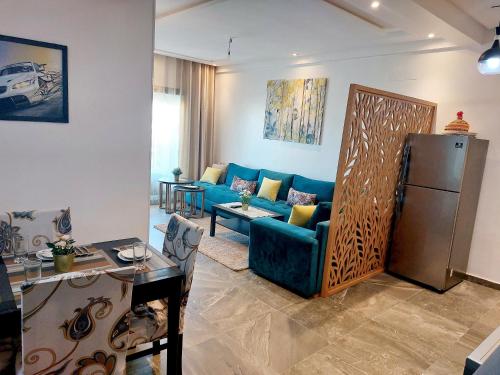 ein Wohnzimmer mit einem blauen Sofa und einem Tisch in der Unterkunft Appart luxury avc piscine & accès direct à la plage in Sidi Rahal