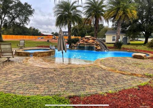 a swimming pool with an umbrella and a fountain at BEAUTIFUL VACATION HOME RENTAL WITH TROPICAl STYLE HEATED POOL & HOT TUB in Alvin