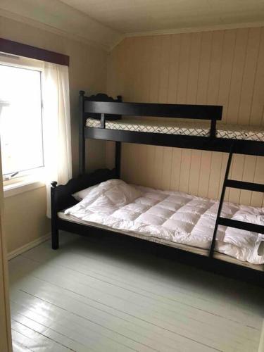 a bedroom with two bunk beds and a window at Mørkveden feriehus, Lofoten in Ramberg