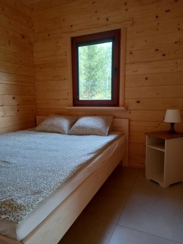 a bed in a log cabin with a window at Domek wypoczynkowy in Wydminy