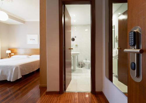 a door to a bedroom with a bed and a bathroom at Hotel Prado Viejo in Moaña