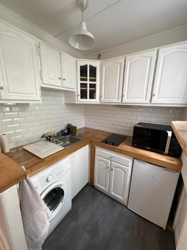 - une cuisine avec des placards blancs, un évier et un lave-linge dans l'établissement Studio idéal proche centre Paris, à Boulogne-Billancourt