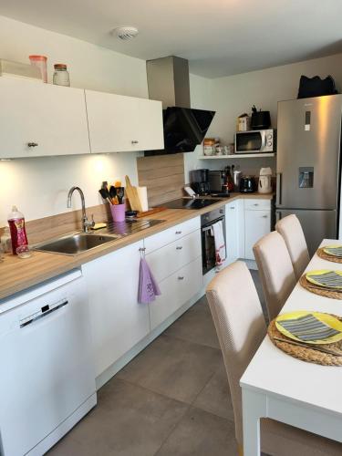 une cuisine avec des armoires blanches et un évier dans l'établissement Gîte bord de mer la Guichardière, à Pirou