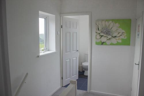 a bathroom with a toilet and a flower painting on the wall at 3-bedroom home with Breakfast, PS4 & Private parking in Swansea