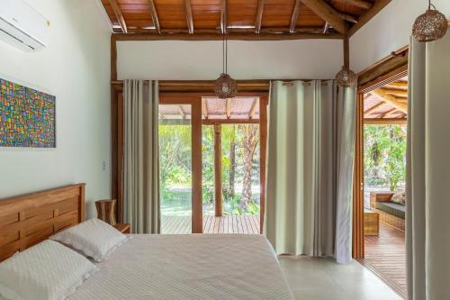 een slaapkamer met een bed en glazen schuifdeuren bij Paraiso do Dende - Barra Grande - Beira Mar in Barra Grande