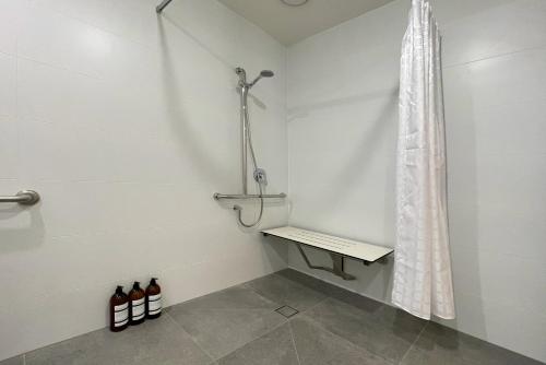 a shower stall with a bench and a shower curtain at Little Island Apartments in Hobart
