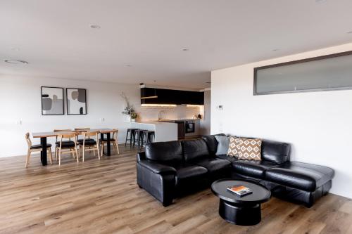 a living room with a black leather couch and a table at Little Island Apartments in Hobart