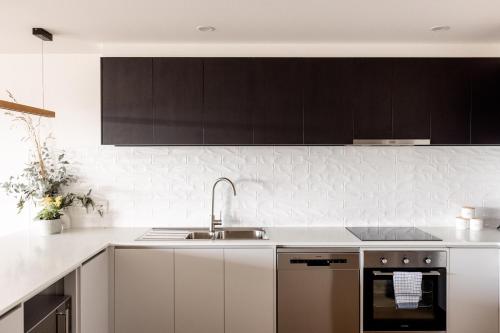 a kitchen with white cabinets and a sink at Little Island Apartments in Hobart