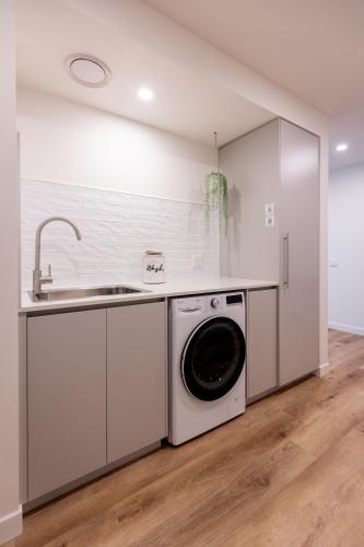 a kitchen with a washing machine and a sink at Little Island Apartments in Hobart