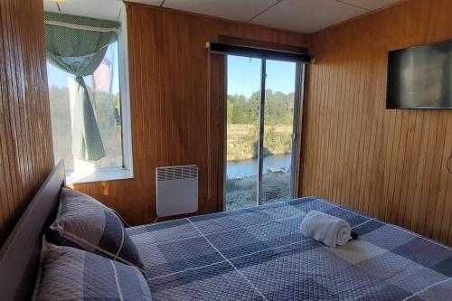 a bedroom with a bed and a large window at Cabaña Carpintero negro in Dalcahue