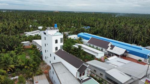- une vue sur un bâtiment blanc avec des palmiers dans l'établissement Khách Sạn Vinhomes Huỳnh Hotel, à Ben Tre