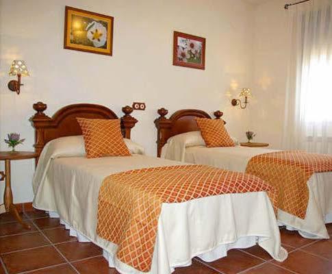 um quarto com 2 camas com lençóis laranja e branco em Casa Rural Cristina I em San Pablo de los Montes