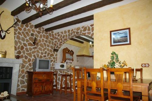 cocina y comedor con mesa y TV en Casa Rural Cristina I, en San Pablo de los Montes