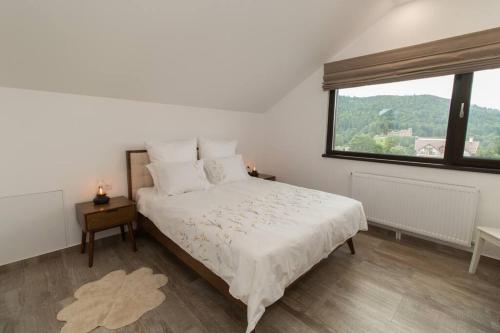 a white bedroom with a bed and a window at Mountain Valley View in Buşteni