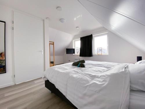 a white bedroom with a large white bed and windows at Lakeview villa with swimming and fishing pier in Simonshaven