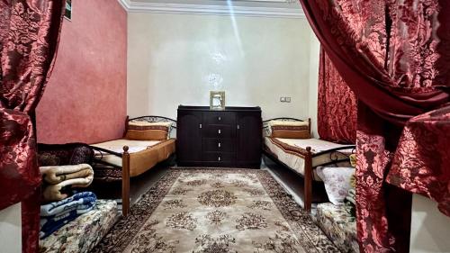 Location appartement meublée Taroudant في تارودانت: غرفة بها كرسيين وخزانة مع ستائر