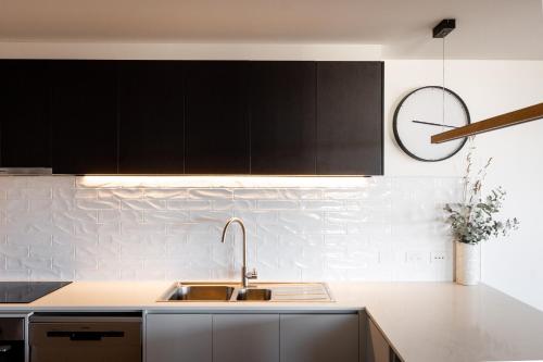 a kitchen with a sink and a clock on the wall at Little Island Apartments in Hobart