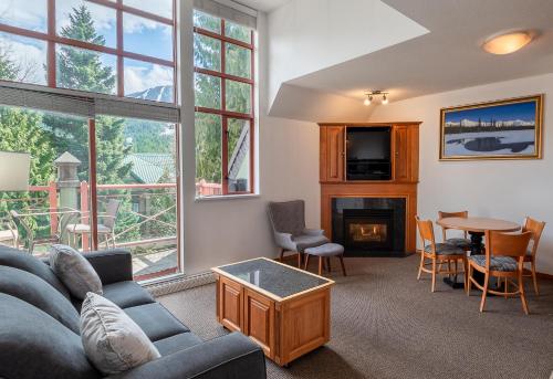 a living room with a couch and a table and a fireplace at Alpenglow Lodge One Bedroom Penthouse by MVA in Whistler