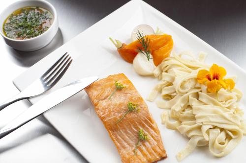 a plate of food with a piece of fish and pasta at Chalets de la Wormsa in Metzeral