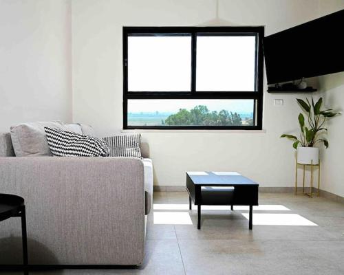 a living room with a couch and a table at נוף עמק החולה דירה חדשה in Gonen