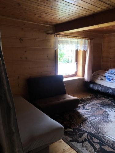 a room with a couch and a window in a log cabin at Stara chałpa oźna in Sól