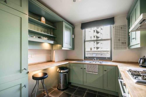 a kitchen with green cabinets and a sink and a window at Stylish City Clerkenwell in London