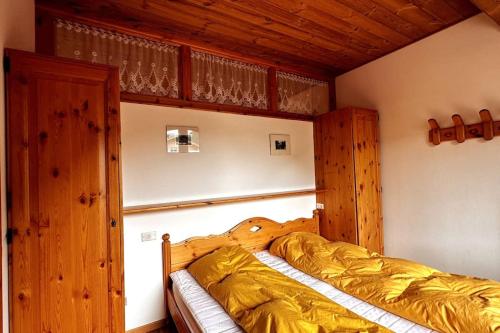 una camera da letto con un letto con lenzuola dorate e pareti in legno di Alta Badia BonHouse a Corvara in Badia
