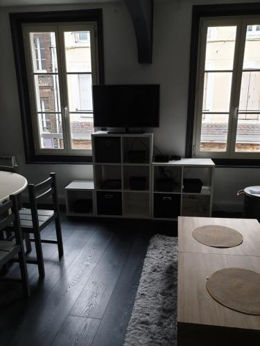 un salon avec une télévision à écran plat et deux fenêtres dans l'établissement Les falaises d Etretat Etretat hypercentre duplex 50m de la mer & parking, à Étretat