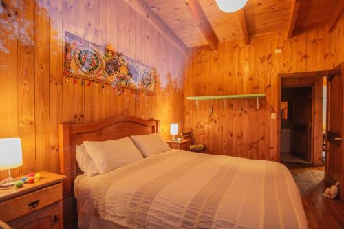 - une chambre avec un lit et un mur en bois dans l'établissement Cabañas Bosques de Puertecillo, à Puertecillo