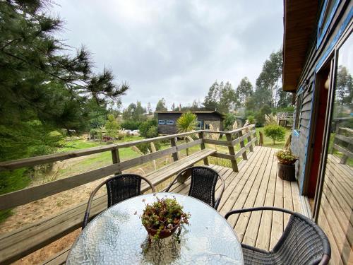 a table and chairs on a deck with a fence at Cabañas Bosques de Puertecillo in Puertecillo
